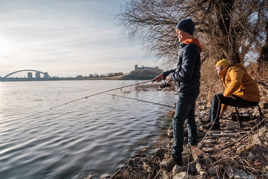 Angler fishing on a boat at Braunig Lake, with lush green surroundings and clear water." 